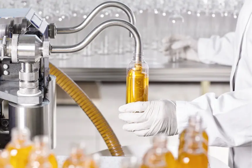 Semi-automatic liquid filling machine filling product bottles on a production line.